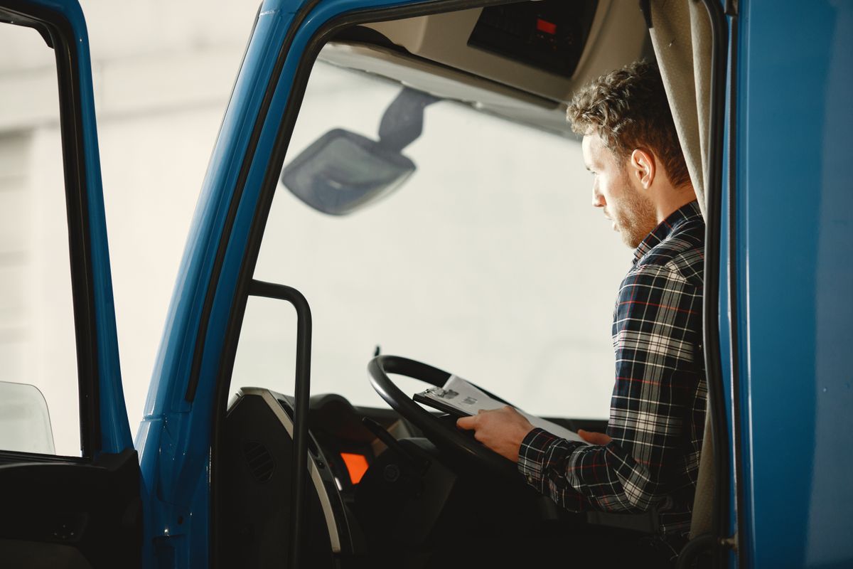 A driver reading a document in the cab of his truck